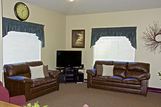 A cozy living room with leather couches, a television, and stylish curtains.