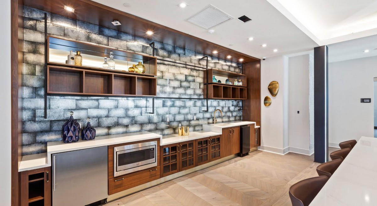 A modern kitchen featuring wood cabinetry, built-in appliances, and a striking brick backsplash.