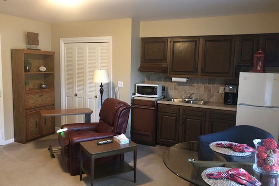 A cozy living area with a kitchenette, featuring an armchair and wooden cabinetry.