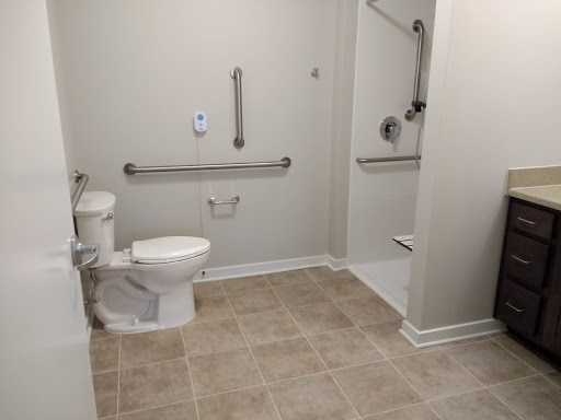 An accessible bathroom featuring grab bars, a toilet, and a walk-in shower.