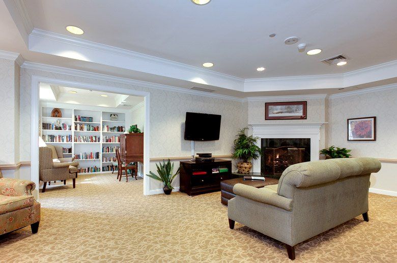 A cozy living room featuring a sofa, fireplace, and a television, with a bookshelf in the adjacent room.