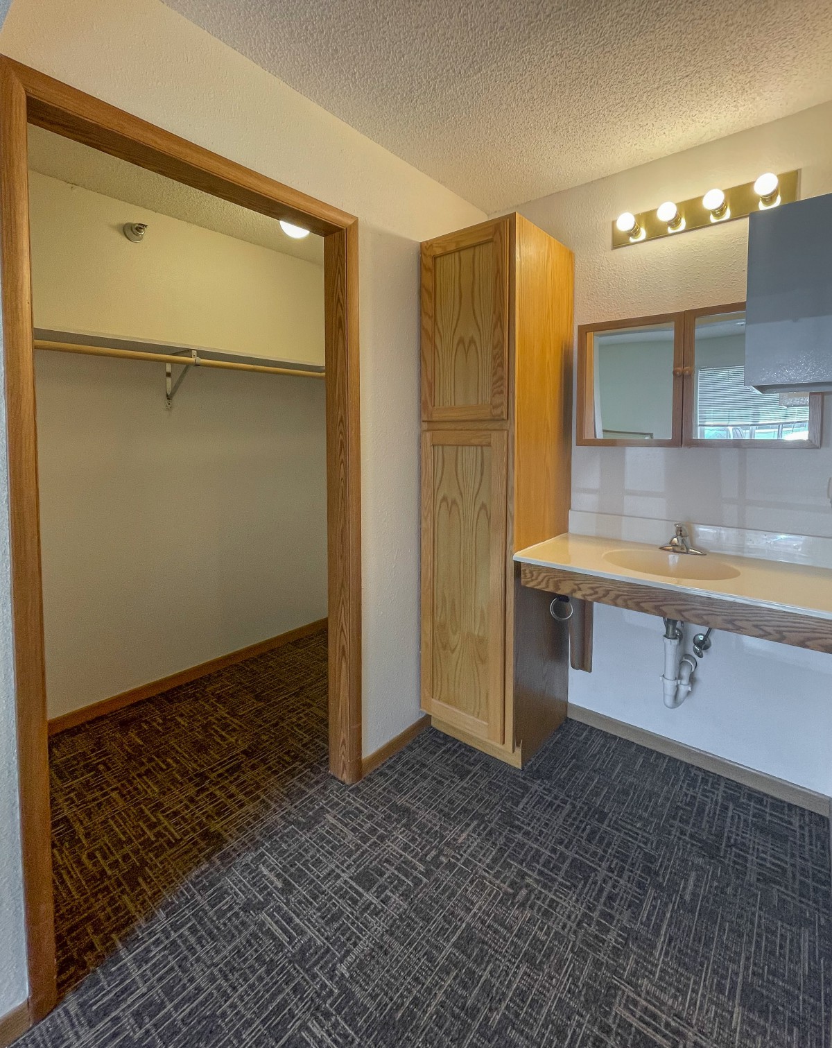 A bathroom with a vanity and sink adjacent to a walk-in closet.