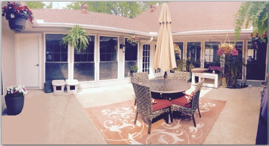 A cozy patio setting with wicker chairs, a table, and an umbrella.