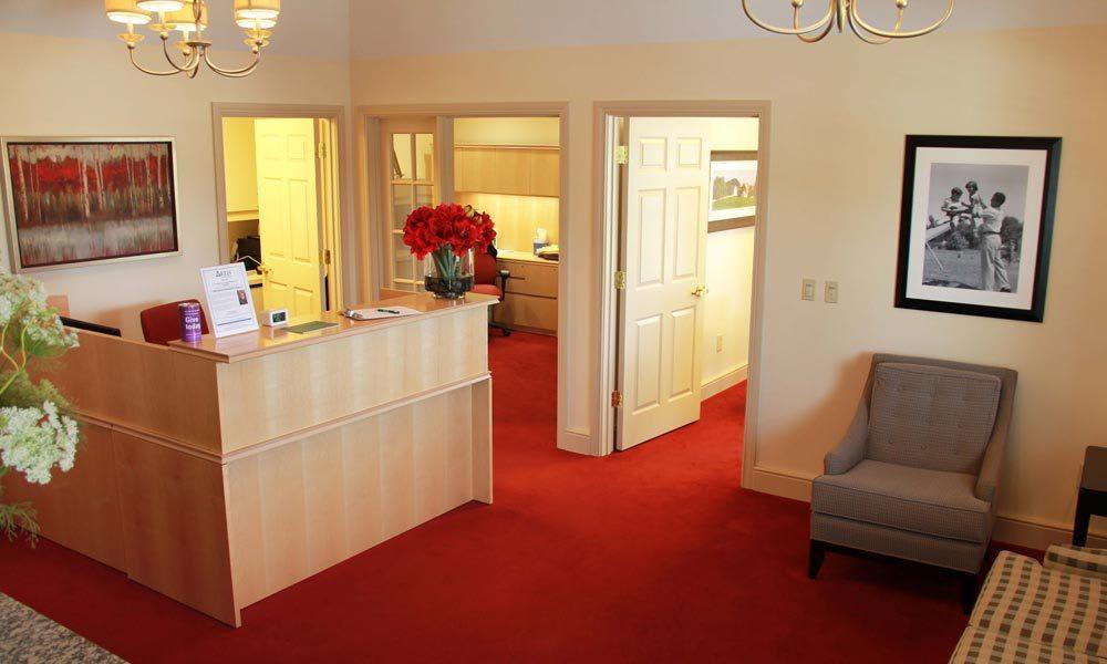 A welcoming office reception area with a desk, red carpet, and comfortable seating.
