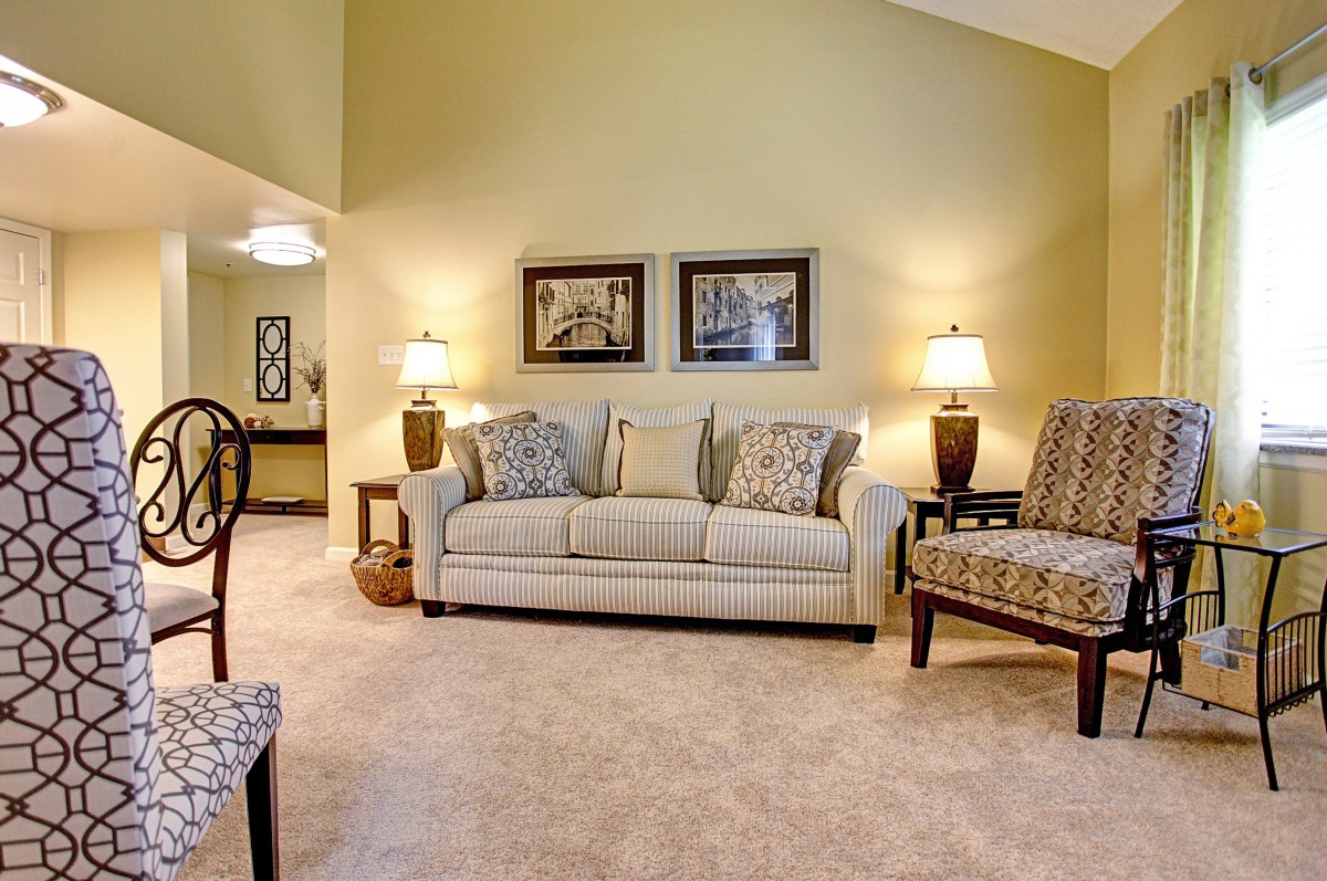 A cozy living room with a beige sofa, accent chairs, and warm lighting.