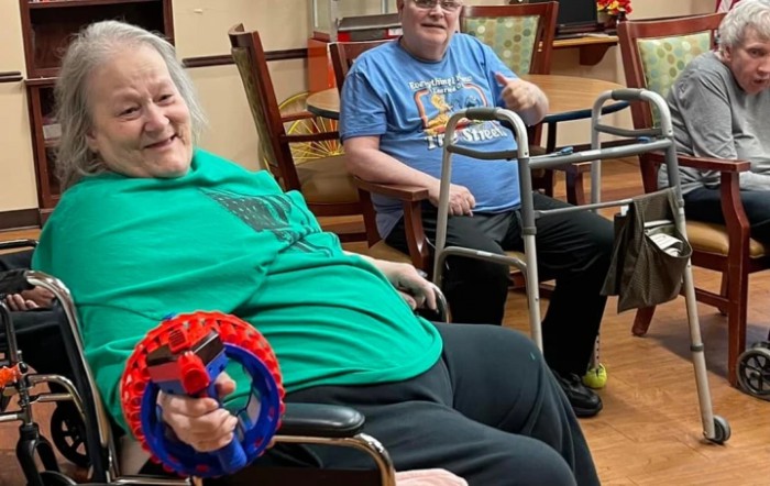 Two elderly individuals enjoying a playful moment indoors, equipped with mobility aids and toys.