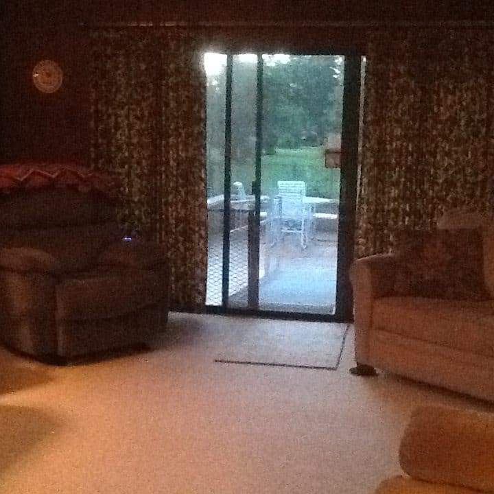 A cozy living room with sofas, an armchair, and a sliding glass door leading outside.