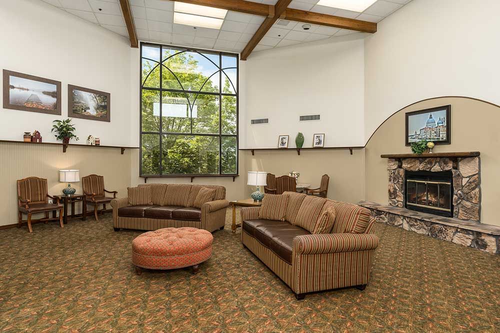 A cozy living room with comfortable couches, a fireplace, and a large window allowing natural light to fill the space.