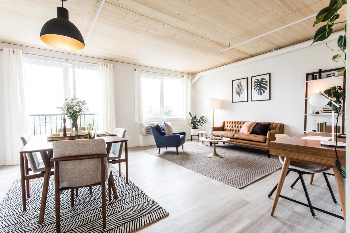 A bright and modern living room with stylish furniture, featuring a wooden ceiling and ample natural light.