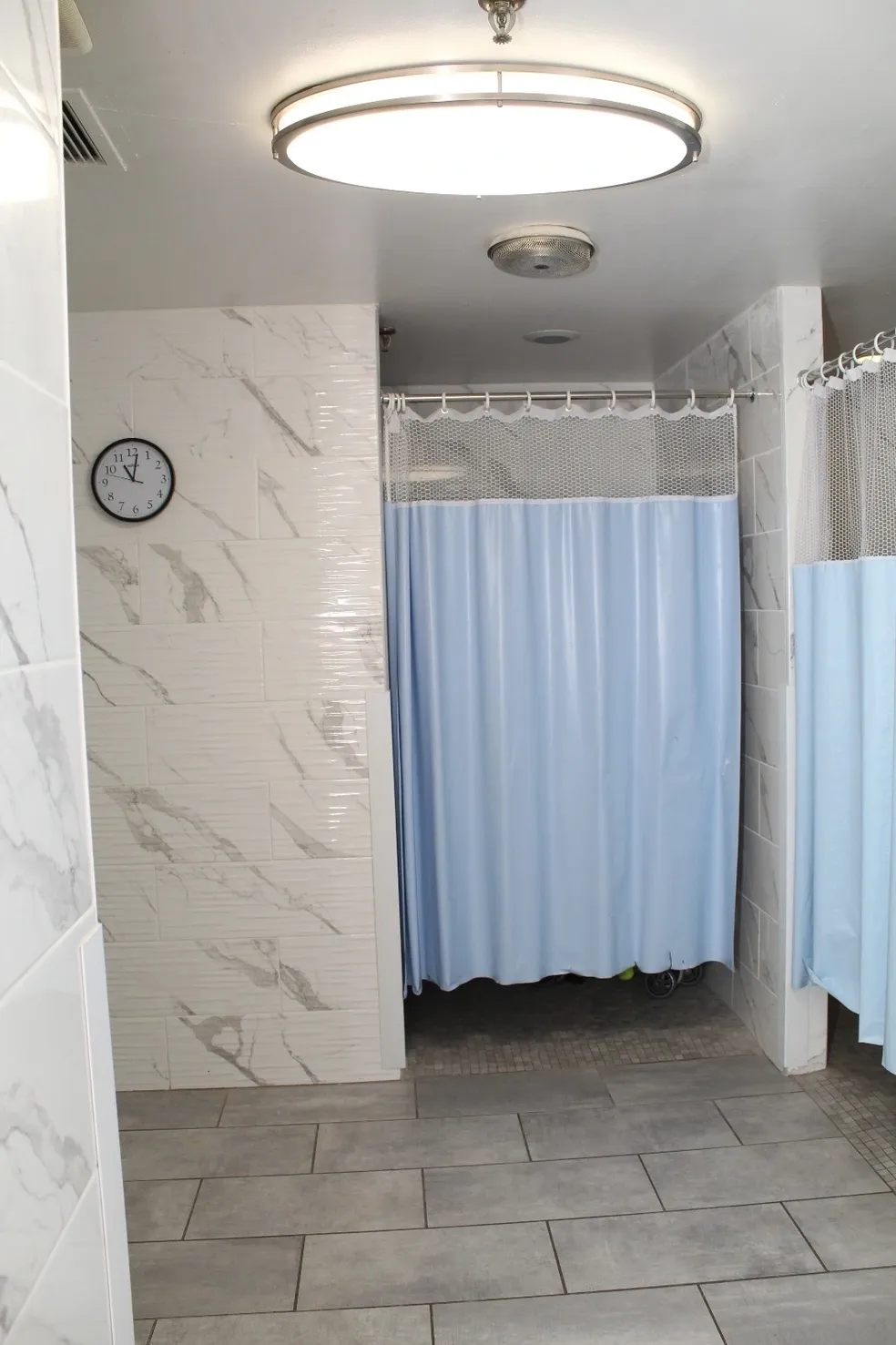 A bathroom with tiled walls and blue shower curtains.