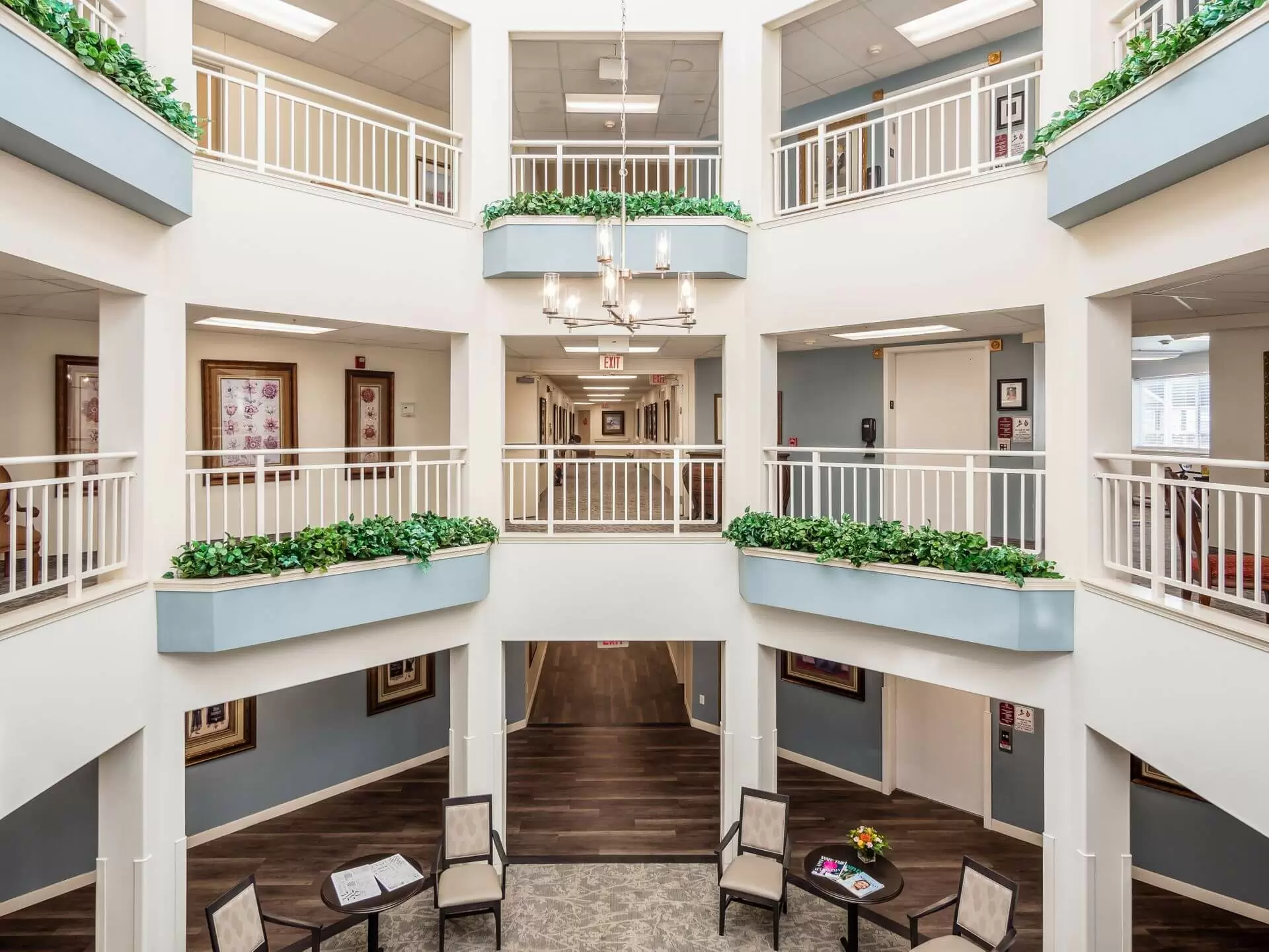 A modern interior atrium with balconies, seating areas, and greenery, reminiscent of a senior living facility.