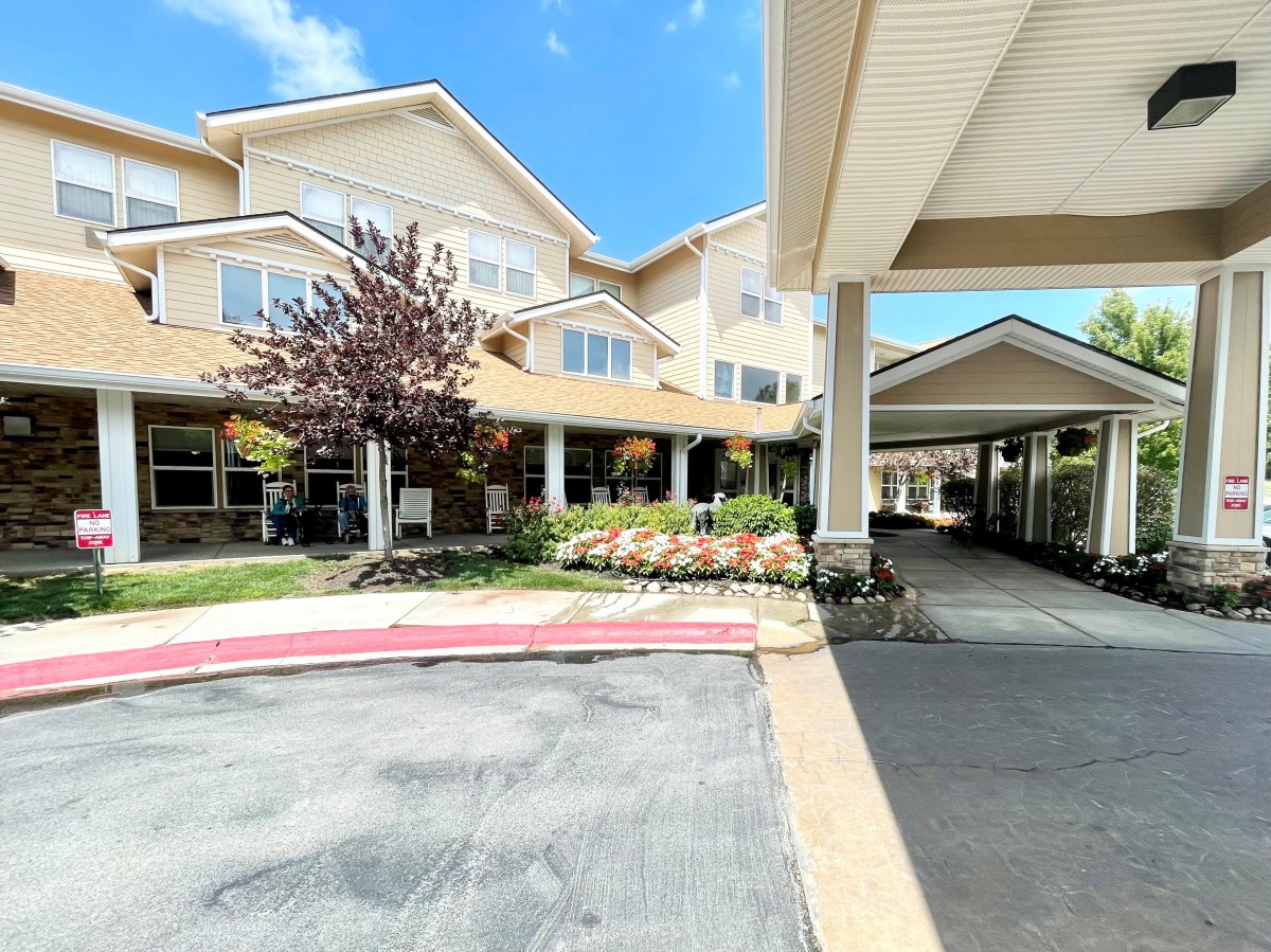 A view of a residential building with a covered entryway and landscaped gardens.