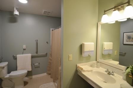 A clean and simple bathroom with a sink, mirror, and shower area.