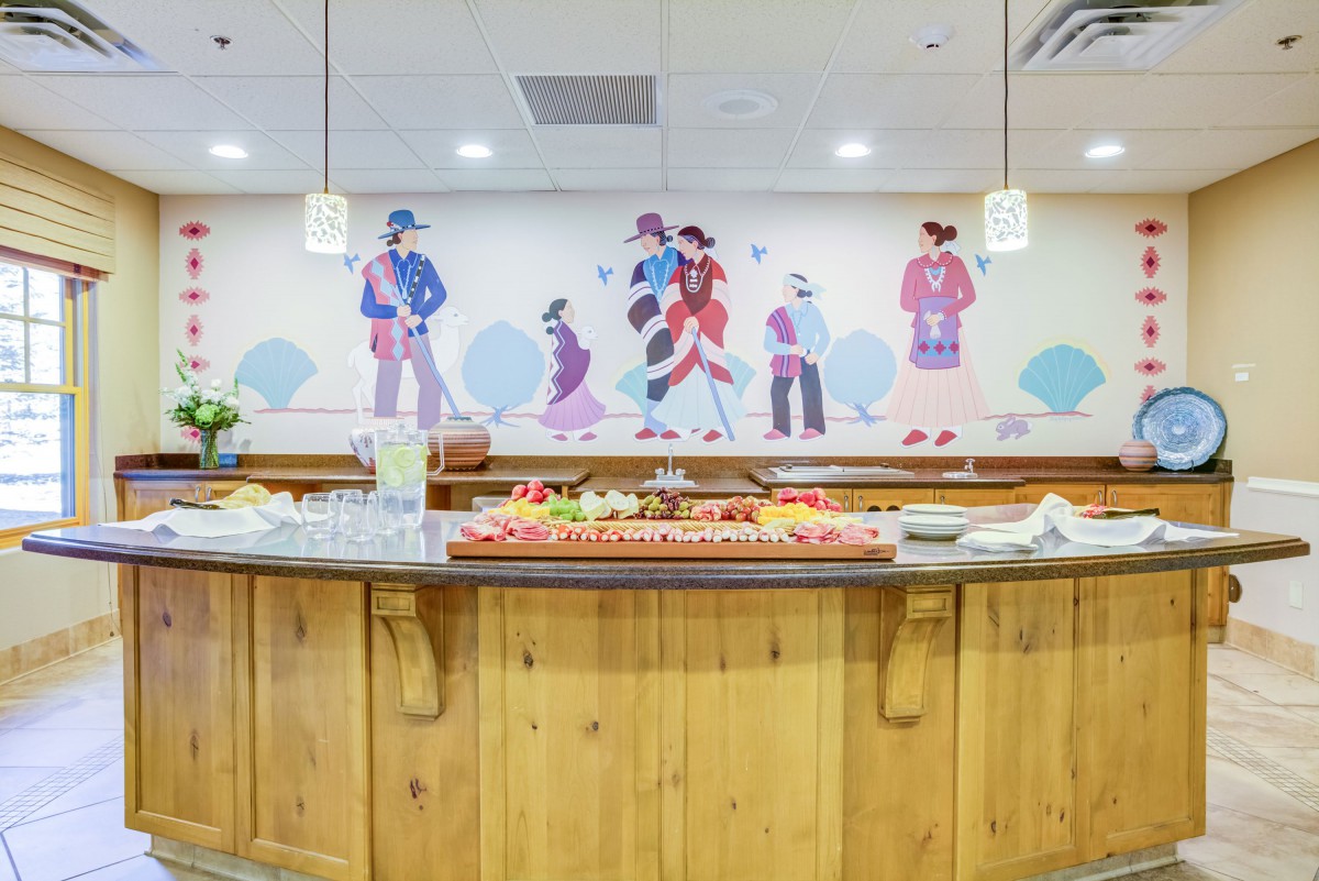 A buffet setup in a restaurant interior with decorative artwork on the wall.