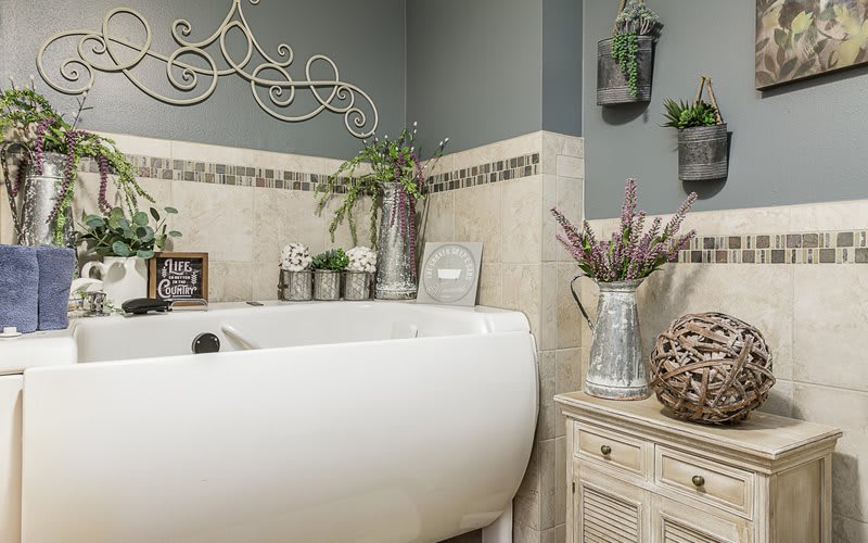A beautifully decorated bathroom with a white bathtub and various plants in vases.