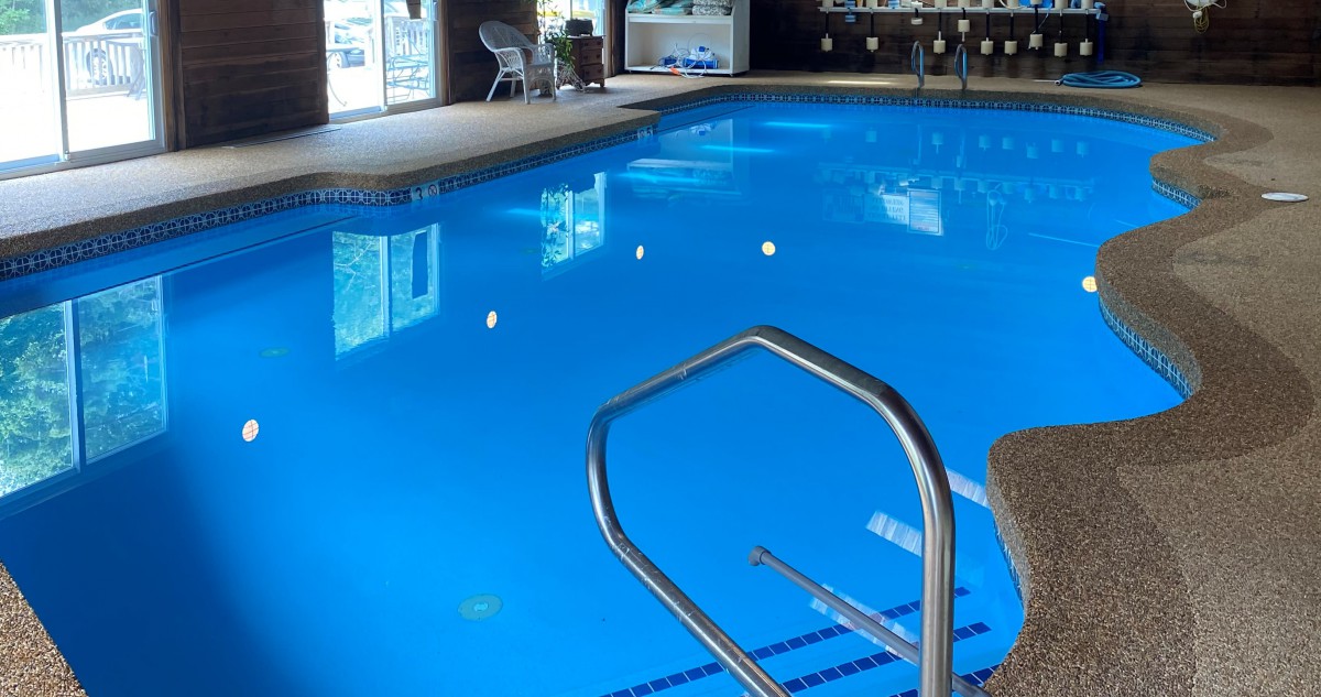 A serene indoor swimming pool with clear blue water and a metal ladder for easy access.