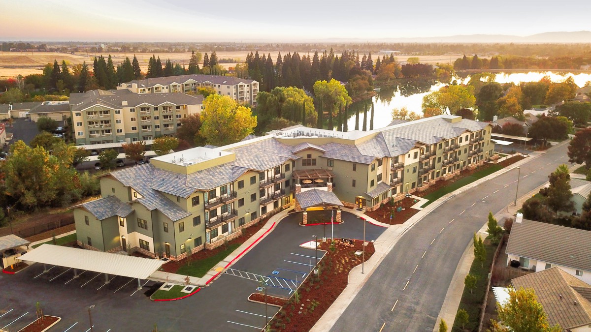 Aerial view of a residential building complex near a river during sunset.