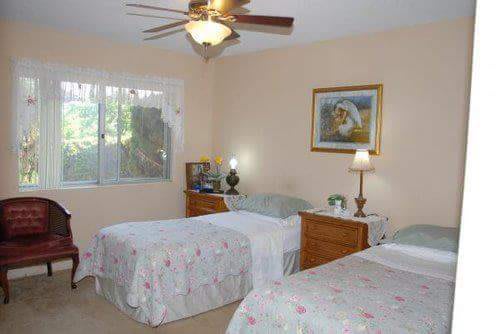 A cozy bedroom with twin beds, a ceiling fan, and warm lighting.