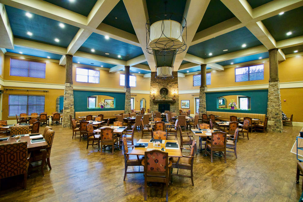 Spacious dining area with multiple tables and chairs, designed with high ceilings and warm lighting.