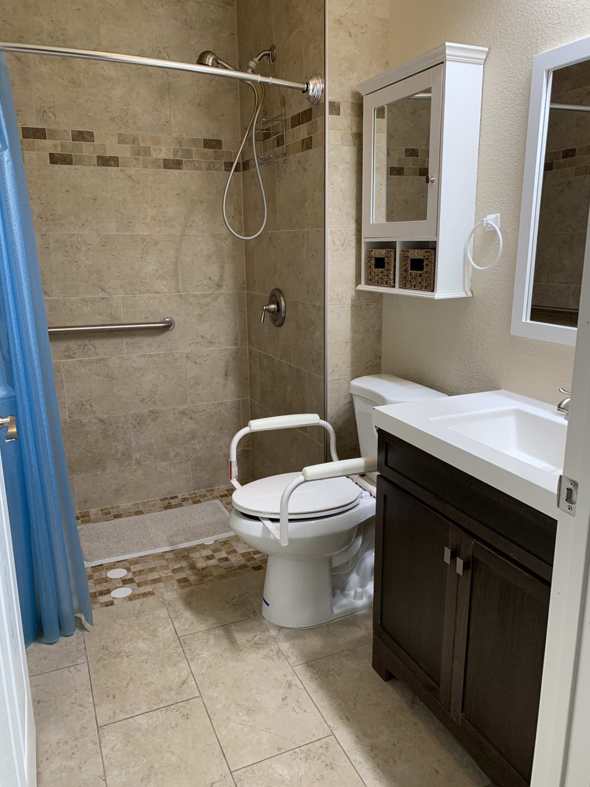 A small bathroom with a shower, toilet, sink, and vanity mirror.