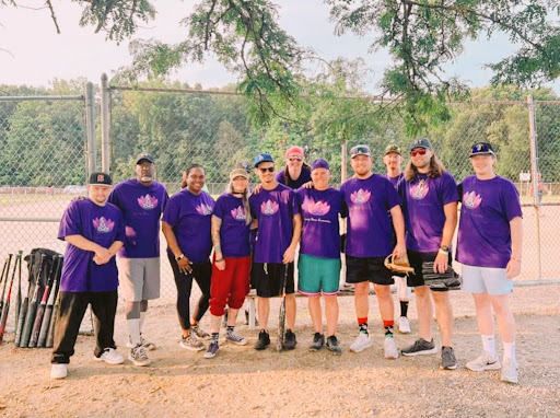 A spirited group of friends gathered for a fun day of softball in vibrant purple team shirts.