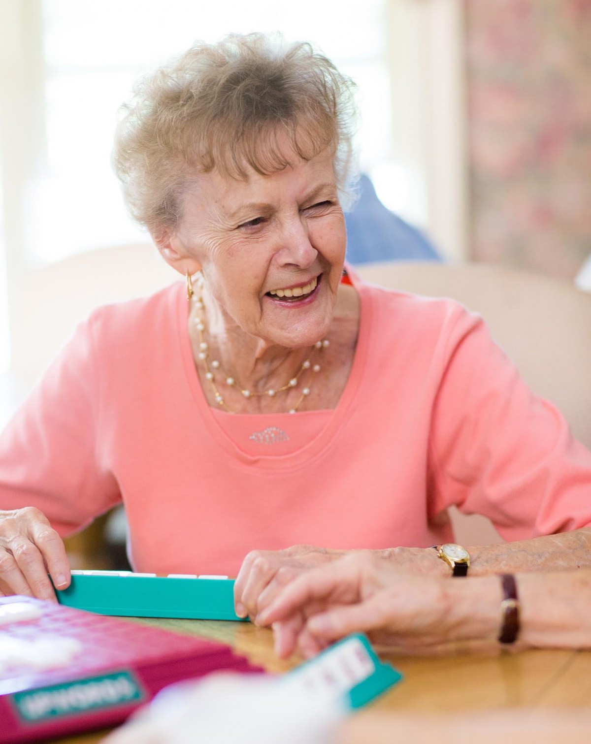 An elderly woman smiling while playing a game indoors.