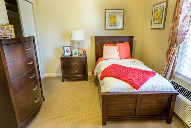 A cozy bedroom with a single bed, wooden furniture, and decorative elements.