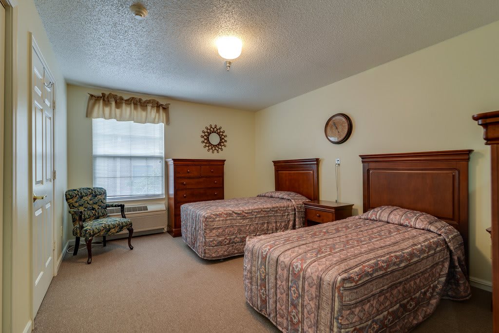 A cozy bedroom with two twin beds and classic wooden furniture.