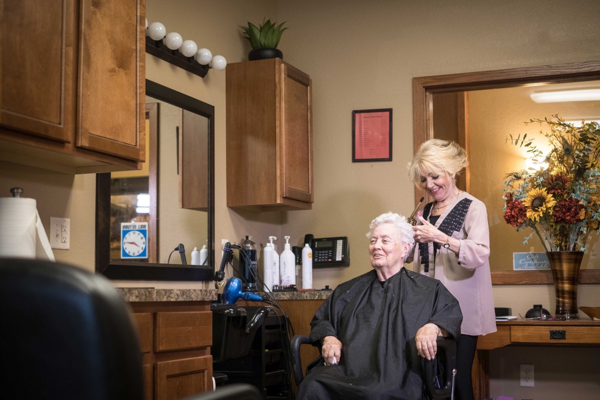 A senior woman getting her hair styled by a hairdresser in a salon.