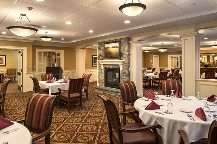 A cozy and elegant dining room with neatly arranged tables and a warm fireplace.