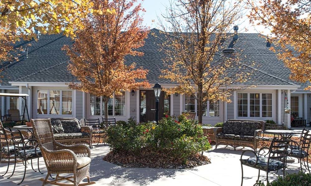 Outdoor seating area surrounded by autumn trees and a building in the background.