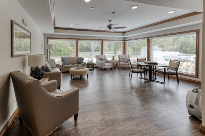 A spacious living room with ample natural light, featuring comfortable seating and wooden flooring.