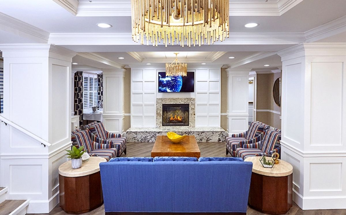 A well-designed living room featuring a blue sofa, fireplace, and elegant chandelier.