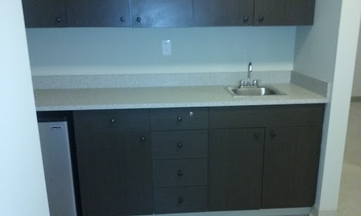 A modern kitchen setup featuring dark cabinetry and a simple sink.