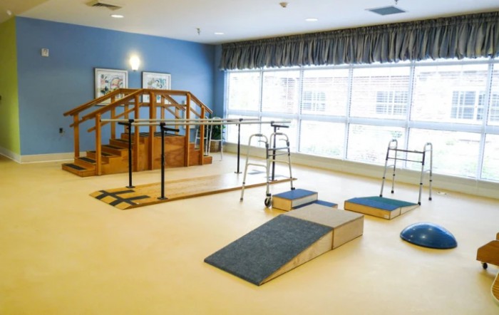 A spacious physical therapy room equipped with rehabilitation tools and exercise ramps.