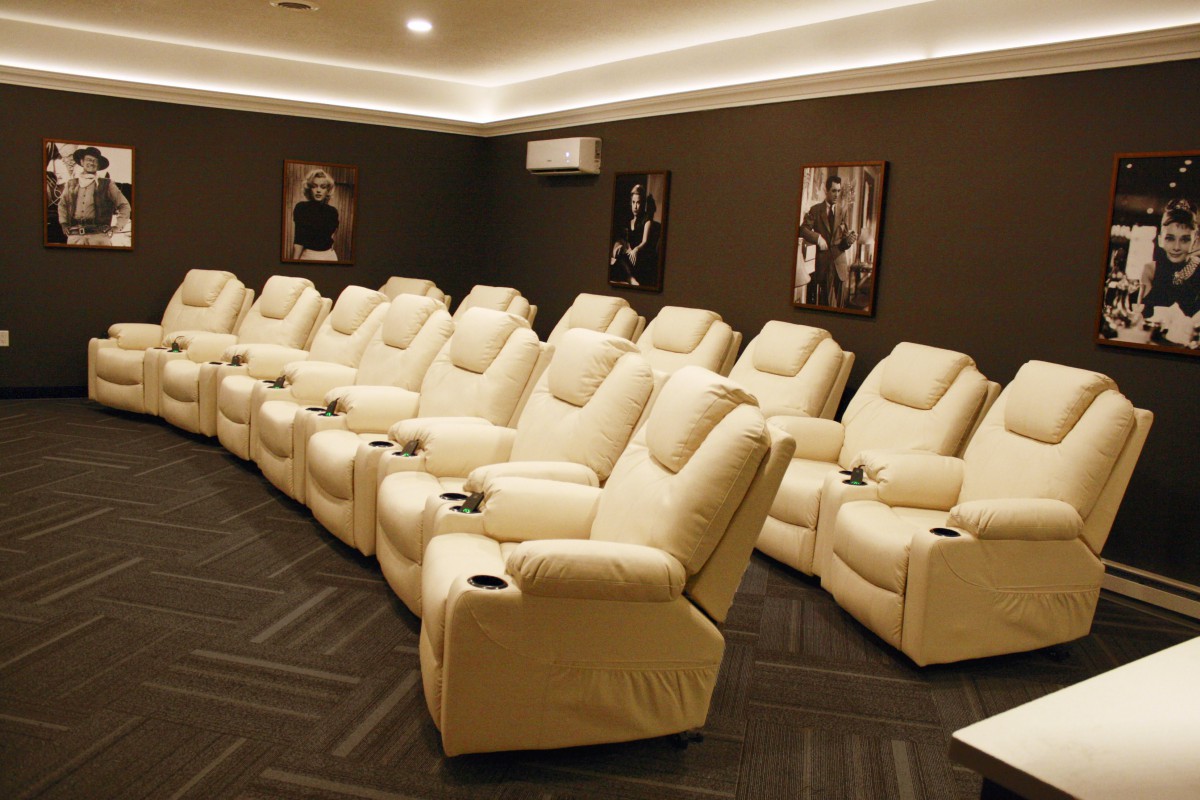 A luxurious home theater with plush recliner seating and movie posters on the walls.