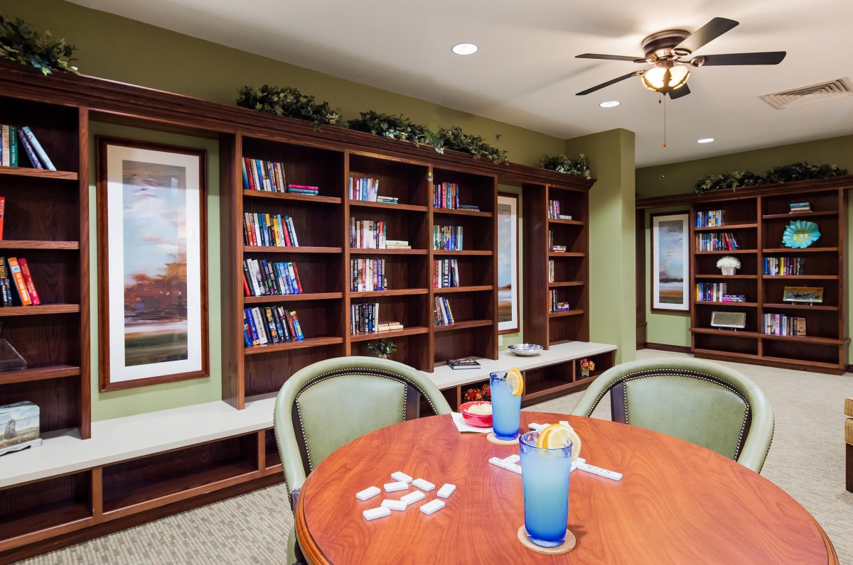 A cozy library space with bookshelves, a table, and chairs, perfect for reading or games.