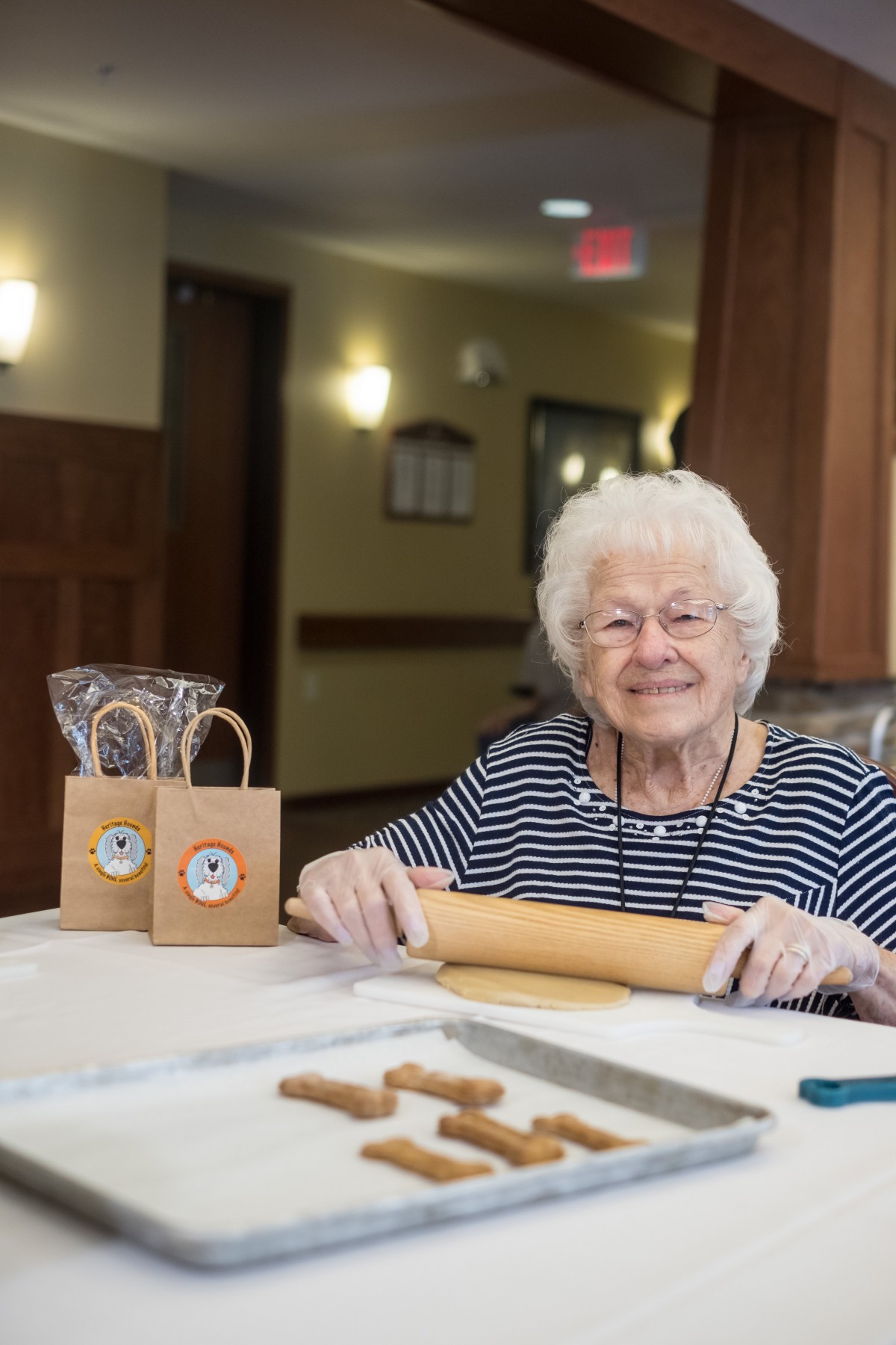 An elderly woman smiling while preparing to bake in a kitchen.