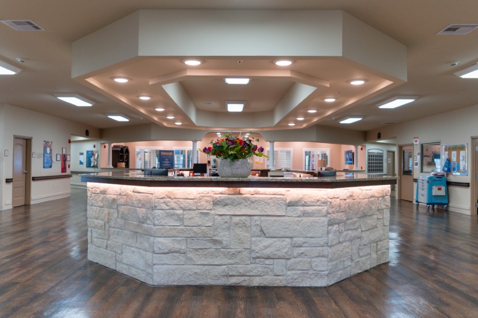 A modern reception area with a stone counter and floral arrangement.