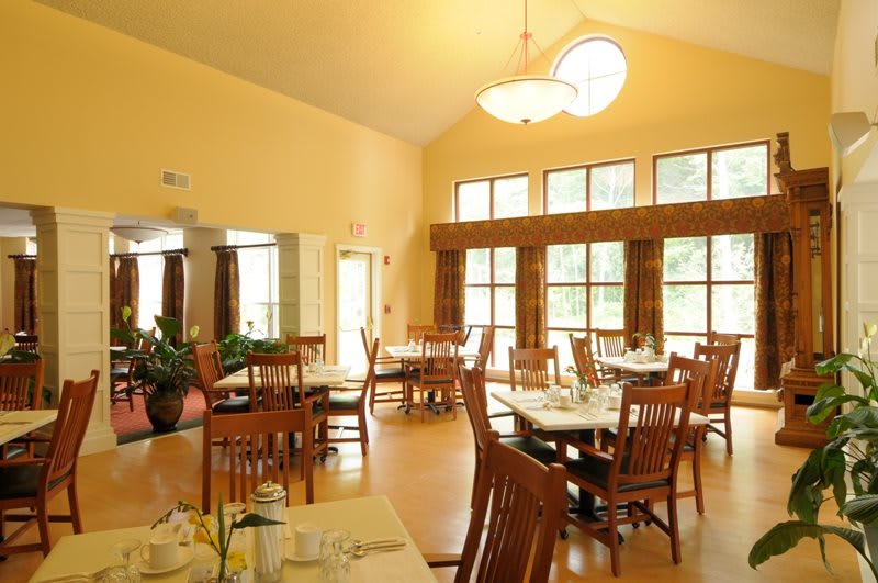A well-lit dining room with neatly arranged tables and chairs.