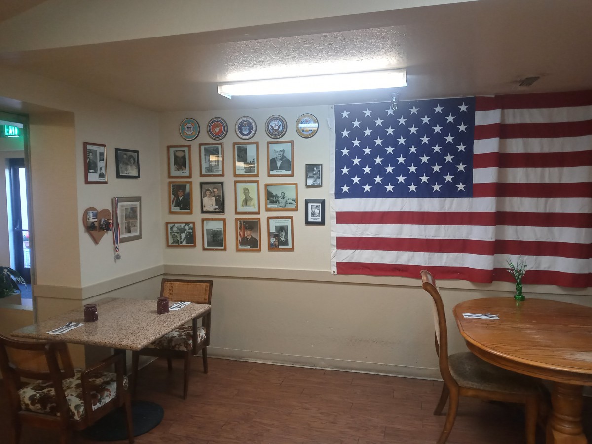 A small dining area with an American flag and various photographs decorating the wall.