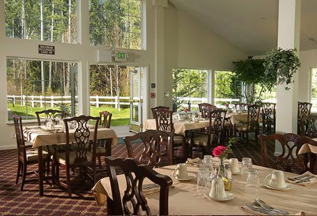 A bright and elegant dining room with large windows offering garden views.