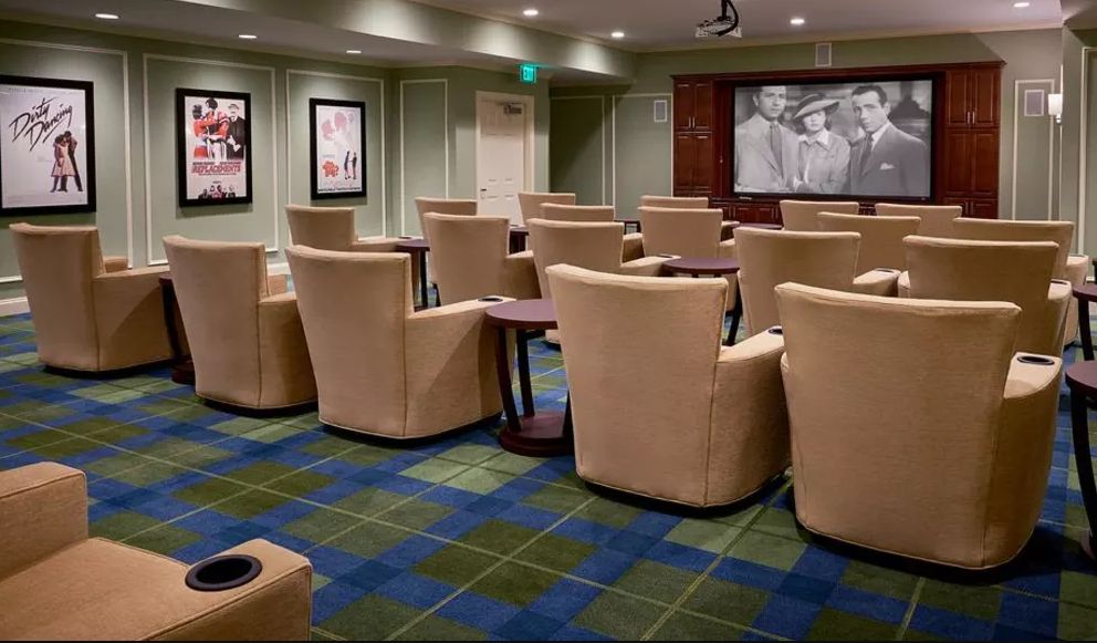 A small theater room with comfortable seating arranged in rows, facing a large screen.