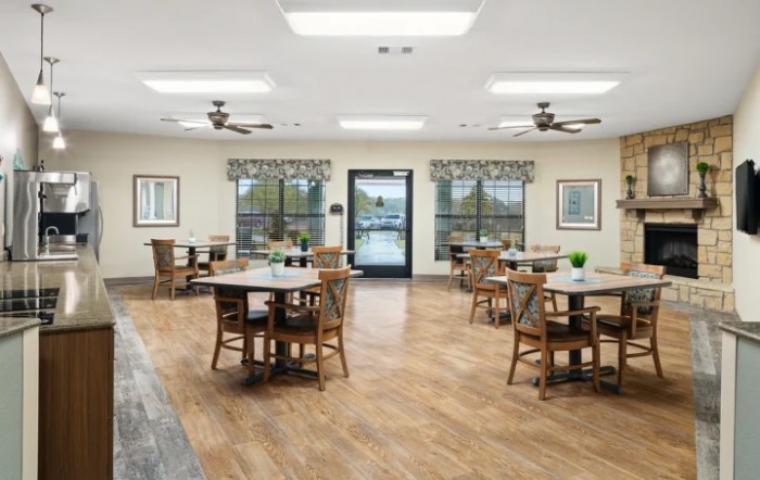 Spacious dining area with wooden flooring and multiple tables and chairs.