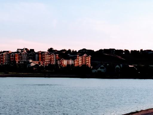 A serene view of a waterfront cityscape at sunset, where the buildings reflect the warm hues of the sky.
