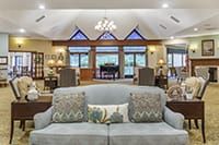 A spacious living room with a sofa, decorative pillows, large windows, and a chandelier.