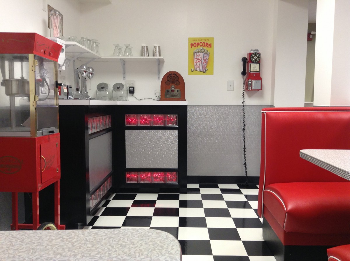 A retro-style diner interior with a classic checkered floor and red booths.