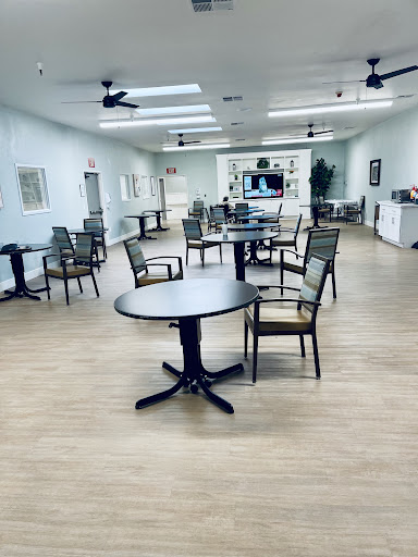A spacious community room featuring multiple tables and chairs, designed for gatherings and activities.