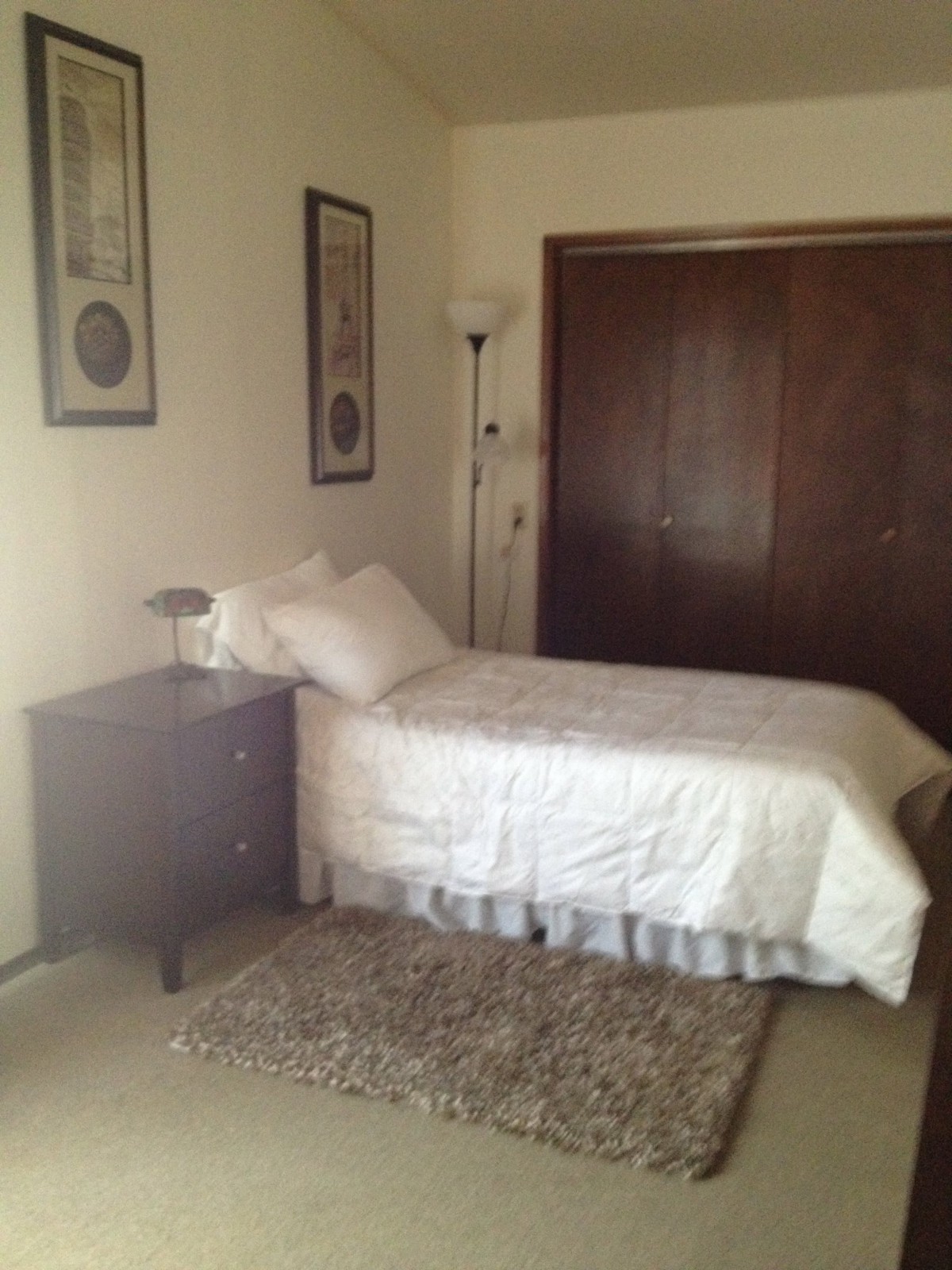 A simple bedroom with a single bed, nightstand, and closet.