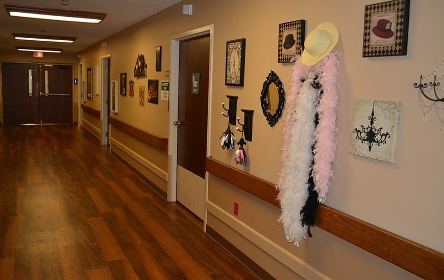 A decorated hallway with framed pictures and a boa draped over a hat.